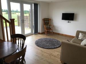 a living room with a couch and a table and a television at The Stables and Granary at Shawbroom Farm in Cheswardine