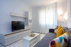 a living room with a couch and a flat screen tv at Apartamentos Los Cantaros in El Puerto de Santa María