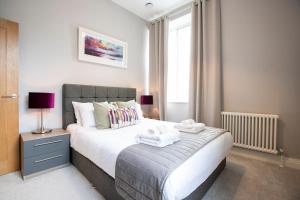 a bedroom with a large bed with two towels on it at Urban Living's - Windsor Castle Luxury Apartments in Windsor
