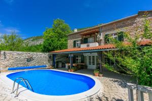 an outdoor swimming pool in front of a house at Santa Barbara in Drivenik