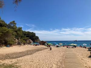 a beach with people sitting on the sand and the ocean at Albatross Mobile Homes on Camping Cala Canyelles in Lloret de Mar