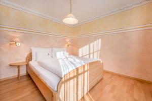 a bedroom with a large bed with white sheets at Haus zur Vogelweide App 4 in Dobbiaco