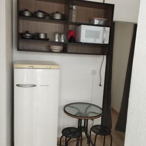 uma cozinha com um frigorífico, uma mesa e bancos em PRAIA ENSEADA - WI-FI e AR CONDICIONADO no Guarujá