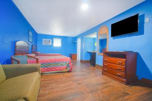una camera da letto con pareti blu, un letto e una TV di Monterrey Motel Padre Island, Corpus Christi BY OYO a Corpus Christi