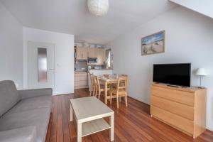 a living room with a couch and a tv and a table at À 300m de la plage, appartement pour 4 in La Baule