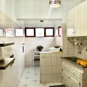 a large kitchen with white tiles and a chandelier at Bright Apartment Close to the Beach & City Center in Praia