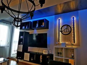 a living room with a blue wall with a tv at RUBIKON -self check in in Osijek