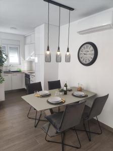 einen Esstisch mit Stühlen und eine Uhr an der Wand in der Unterkunft Modern Apartment Adria Relax with private heated pool in Trogir
