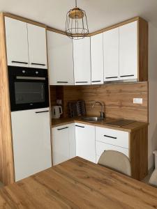 una pequeña cocina con armarios blancos y fregadero en Apartman Green, en Šišava