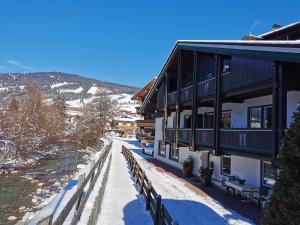 un bâtiment avec de la neige sur le sol à côté d'une clôture dans l'établissement Haus am Bach, à Kirchberg in Tirol