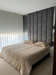 a bedroom with a large bed with a large headboard at Pé na Areia in Póvoa de Varzim