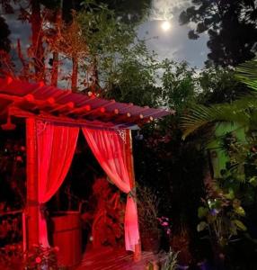 a red tent with a red curtain in a garden at Pousada Chalés Canto do Rio in Visconde De Maua