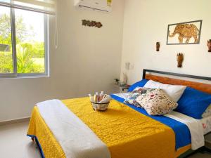 um quarto com uma cama com um cobertor amarelo e uma janela em CASA PALMA ROJA BOUTIQUE , PISCINA PRIVADA em Carmen de Apicalá