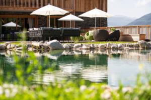 una piscina de agua con sillas y sombrillas en Lerchpeuntgut Alpenfreud Apartments, en Tamsweg