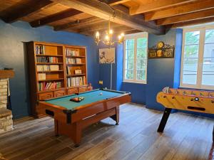 Habitación con mesa de billar y estantería. en Le Moulin Etourneau - 3 gîtes avec 2 piscines, en Champagnac