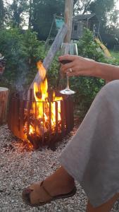 Eine Frau sitzt vor einem Feuer in der Unterkunft O'Noire, Viroinval Treignes in Treignes