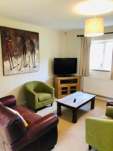 a living room with a couch and a tv at Canons Court Mews in Wotton under Edge