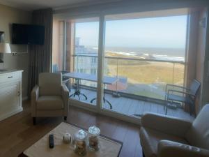 a living room with a view of a balcony at Zeezicht, Kanaalweg 1-408 in Cadzand