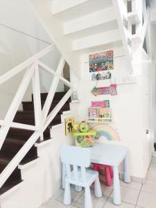 Una mesa blanca y una silla en una habitación con escaleras en De'Manda Homestay en Sandakan