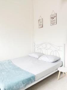 a white bedroom with a bed and a chair at De'Manda Homestay in Sandakan