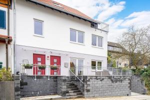 a white house with a red door and stairs at EasyGreen moderenes Appartment - Essen by EasyHood in Essen