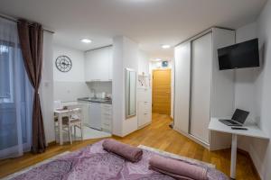 a living room with a bed and a desk with a laptop at Sky Apartments Novi Sad in Novi Sad