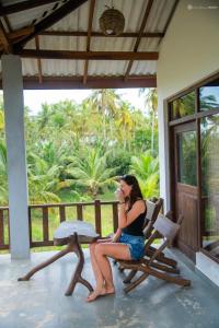 Una donna seduta su una sedia in veranda di ohm lagoon home a Tangalle