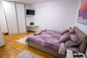 a bedroom with a bed and a table with a laptop at Sky Apartments Novi Sad in Novi Sad