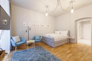 sypialnia z łóżkiem i dwoma niebieskimi krzesłami w obiekcie Vienna City Apartments Krongasse w Wiedniu