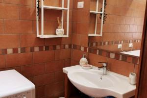 a bathroom with a white sink and brown tiles at Villa di montagna sul cammino della Via degli Dei 