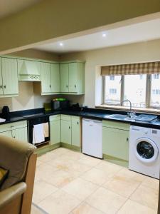 a kitchen with green cabinets and a washing machine at Canons Court Mews in Wotton under Edge