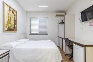 Habitación con cama, escritorio y TV. en Hotel Lisbor, en Francisco Beltrão
