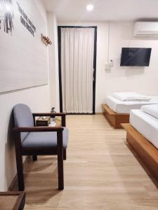 a room with two beds and a chair and a television at Sleep Walker Poshtel in Chiang Mai
