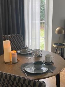 einen Holztisch mit Tellern, Gläsern und einer Kerze in der Unterkunft Kraków Green Hill Luxury Apartment in Balice