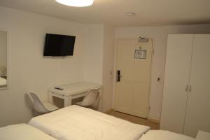 Schlafzimmer mit einem Bett, einem Schreibtisch und einem TV in der Unterkunft Platia - rooms in Günzburg