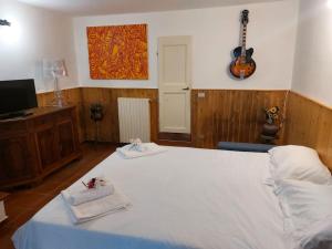 Un dormitorio con una cama blanca y una guitarra en la pared en Villa Tutti i colori del Chianti, en Linari