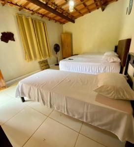 two beds in a room with white sheets at Pousada Ponte da Ceroula in Palmeiras