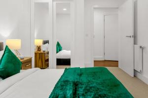 a bedroom with a bed with a green blanket on it at One Bedroom Serviced Apartment in Islington in London