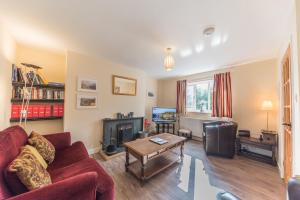 a living room with a red couch and a table at Lavender Cottage Coniston in Coniston
