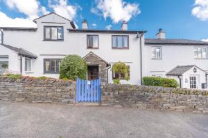 a white house with a stone wall and a blue gate at Lavender Cottage Coniston in Coniston