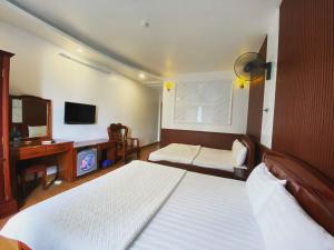 Un dormitorio con dos camas y un escritorio y un televisor. en Khách Sạn Kim Tiến, en Ha Long