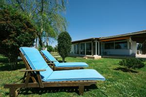 two lounge chairs sitting in the grass in front of a house at Stella's Holiday Resort in Tigaki