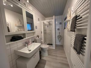 een witte badkamer met een wastafel en een toilet bij Ferienwohnung zur alten Post 
