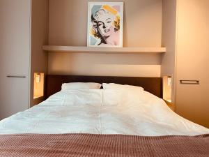Un dormitorio con una cama blanca con un cuadro en la pared. en Luxe appartement Cadzand-Bad, en Cadzand 15 fotos más
