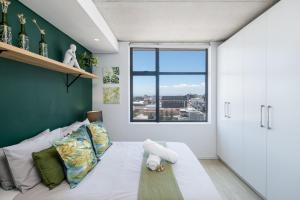 1 dormitorio con cama blanca y pared verde en Modern Two Bedroom Unit, Mountain & Harbour Views, en Ciudad del Cabo