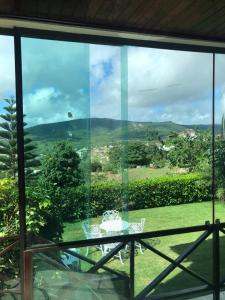 una mesa de cristal y sillas frente a una ventana en CASA AUGUSTA, Gravatá-PE, en Gravatá