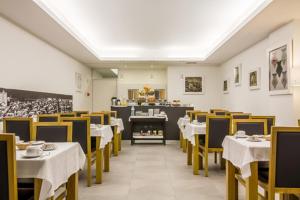 uma sala de jantar com mesas brancas e cadeiras amarelas em Hotel Laranjeira em Viana do Castelo