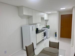 cocina blanca con armarios blancos, mesa y sillas en 2 quartos próximo a praia, en Maceió