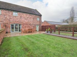 a brick house with a lawn in front of it at Oak Barn in Sandbach