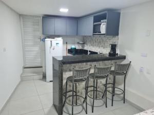 a kitchen with three bar stools and a refrigerator at Pousada Beach Claudia in Maragogi